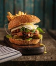 Burger with chopped meat, egg and arugula on a wooden table Royalty Free Stock Photo