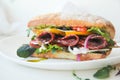 Burger ciabatta with smoked sausage, fresh salad mix, tomatoes, pesto sauce and onions