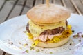 Burger with a coarse meat patty, cheese, mayonnaise and saffron cabbage salad, garnished with spices and radish sprouts on a white Royalty Free Stock Photo