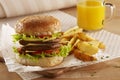 Burger with double meat and cheese, potato wedges and orange juice. Ready to eat Royalty Free Stock Photo