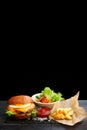 Burger with egg with fries and ketchup sauce on wooden table and black background. tasty cheesburger Royalty Free Stock Photo