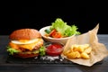 Burger with egg with fries and ketchup sauce on wooden table and black background. tasty cheesburger Royalty Free Stock Photo