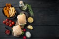 Burger with fish fingers fresh lettuce, tomato and tartar sauce, on wooden cutting board, on black wooden table background, top Royalty Free Stock Photo