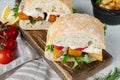 Burger with fish fingers fresh lettuce, tomato and tartar sauce, on wooden cutting board, on white background Royalty Free Stock Photo