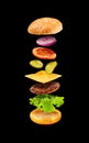 Burger with flying ingredients on black background. Royalty Free Stock Photo