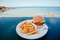 Burger with french fries ready for dinner in a plate. Seaside vacation with food in outdoor restaurant Royalty Free Stock Photo