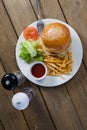 Burger, french fries, sauce in plate on wooden table