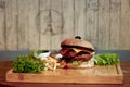 Burger with french fries and vegetables on wooden board, closeup Royalty Free Stock Photo