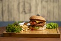 Burger with french fries and vegetables on wooden board, closeup Royalty Free Stock Photo