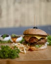 Burger with french fries and vegetables on wooden board, closeup Royalty Free Stock Photo