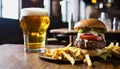 A burger and fries on a table next to a glass of beer Royalty Free Stock Photo