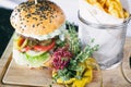 Burger with fries and vegetables on a board. Dinner main dish on a wooden table. Traditional polish cuisine