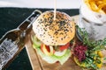 Burger with fries and vegetables on a board. Dinner main dish on a wooden table. Traditional polish cuisine