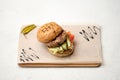 Burger ingredients, Sesame grilled Bun with fried meat, fresh cucumber and tomato served on parchment paper. Tasty snack