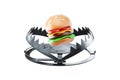 Burger in a large metal bear trap, close-up. The concept of gluttony, obesity, fast food, addiction, malnutrition. 3D render, 3D