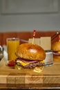 Burger meal closeup - main course american burger with fries on a wooden underlay with orange juice