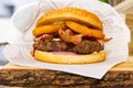 Burger in paper packaging on a wooden beard. delicious burger on a wooden serving board.