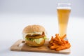 Burger with spicy French fries by beer glass Royalty Free Stock Photo