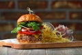 Burger on the wooden table with cheese, bacon, tomatos, green and red salad and french fries