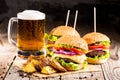 Burgers with beef and fried potatoes and glass of cold beer