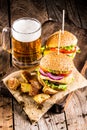 Burgers with beef and fried potatoes and glass of cold beer Royalty Free Stock Photo