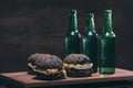 Burgers with black bun and bottles on wooden kitchen desk Royalty Free Stock Photo