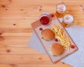 Burgers, fried potatoes and mugs of beer on wooden table. Top view, copy space Royalty Free Stock Photo