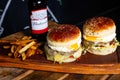 burgers, fries and beer on top of a wooden tray