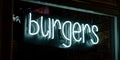 Burgers inscription in neon lights at night. Electric sign at night nightlife concept. Modern fluorescent life style Royalty Free Stock Photo