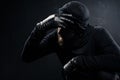 Burglar in balaclava leaning his head