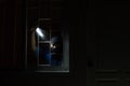 Burglar breaking in to home in night through window. Burglar at night with flashlight at window of the house Royalty Free Stock Photo