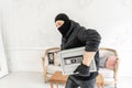 The burglar commits a crime in Luxury apartment with stucco. Thief with black balaclava stealing modern Electronic safe