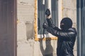 A masked man breaks a window with a crowbar. Garage robbery. Burglar with obscured face trying to break the window. Robbery of a Royalty Free Stock Photo