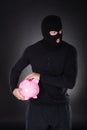 Burglar stealing a pink piggy bank