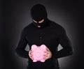 Burglar stealing a pink piggy bank