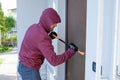 Burglar trying to force a door lock using a crowbar