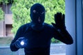 Burglar wearing a balaclava looking through the house window Royalty Free Stock Photo