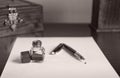 Burgundy fountain pen, blue ink and inkwell on white paper sheet Royalty Free Stock Photo