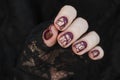 Burgundy golg cracle matte nail polish. Manicured nail with dark matte nail polish isolated on black