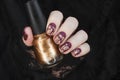 Burgundy golg cracle matte nail polish. Manicured nail with dark matte nail polish isolated on black Royalty Free Stock Photo