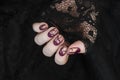 Burgundy golg cracle matte nail polish. Manicured nail with dark matte nail polish isolated on black