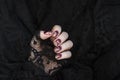 Burgundy golg cracle matte nail polish. Manicured nail with dark matte nail polish isolated on black