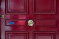 Burgundy red color painted wooden door with antique shiny brass doorknob and key lock. Flaking red paint and blue painted layer. Royalty Free Stock Photo