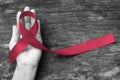 Burgundy ribbon awareness symbolic concept for multiple myeloma cancer and Sickle-Cell Anemia on person`s hand support Royalty Free Stock Photo