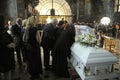 Burial service in a church. Relatives in black mourning clothes giving the last farewell to late lying in white coffin