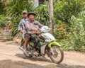 Two Thai men on a scooter, in a rural area