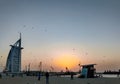 Burj Al Arab during a beautiful golden sunset shot from the Jumeirah beach with lots of seagulls | luxury seven star hotel