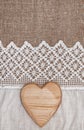 Burlap background with lacy cloth and wooden heart Royalty Free Stock Photo