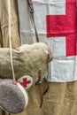 Burlap bag with a red cross and a flask against the background of a field hospital tent canvas