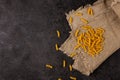 Burlap napkin on a dark structural background, top view. A scattering of macaroni on it Royalty Free Stock Photo